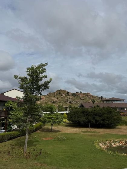 Another perspective on a cloudy day, showing the guest rooms and the hills. The mood is calm and introspective, perfect for a wellness journey.