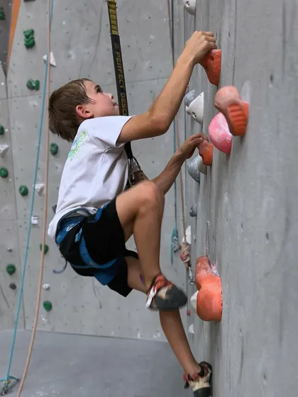 A young climber carefully plans his next move. Every climb is a puzzle that builds physical and mental strength.