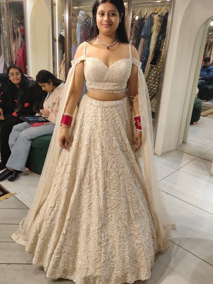 A beautiful bride-to-be in an off-white chikankari lehenga with an off-shoulder blouse and a sheer cape. It's a modern, elegant, and timeless look.