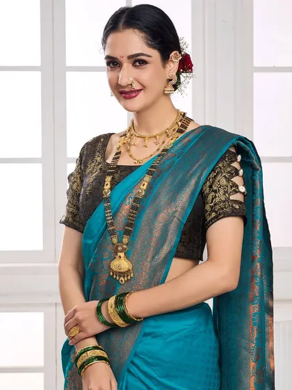 This image captures a model wearing a traditional Maharashtrian jewellery set against a blue silk saree. The focus is on the layered necklaces and the model's serene expression, suitable for festive and bridal collection promotions.