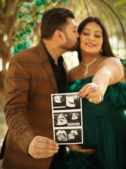 A close-up shot filled with love and emotion. The dad-to-be gives his partner a sweet kiss on the cheek as they proudly display their sonogram.