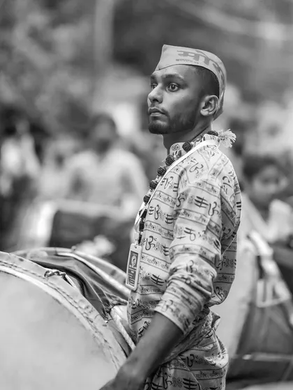A black and white profile portrait of a dhol player, his gaze fixed and ready.