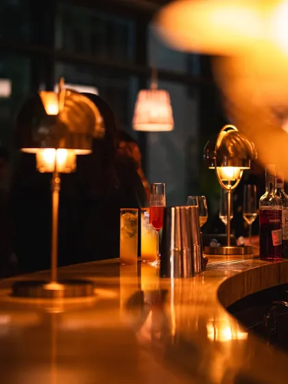The warm glow of the bar top, reflecting the ambient light from our table lamps. It's the perfect spot to enjoy a quiet drink or watch the action unfold.