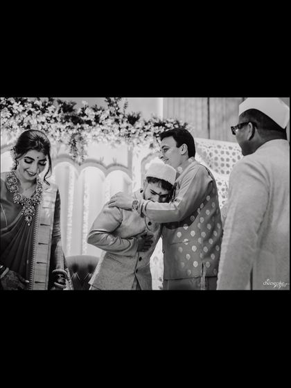 A black and white shot capturing a heartfelt embrace between the groom and his father.