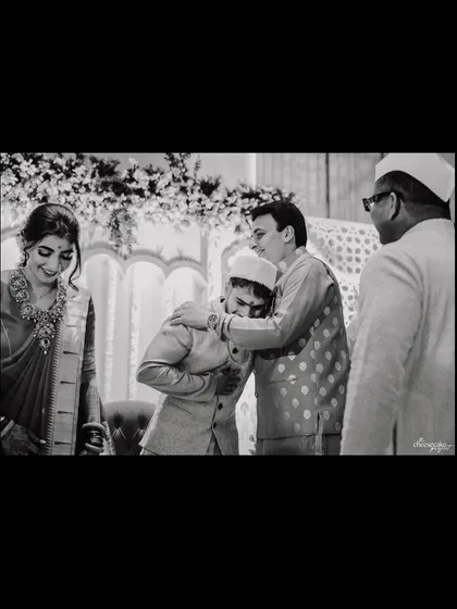 A black and white shot capturing a heartfelt embrace between the groom and his father.