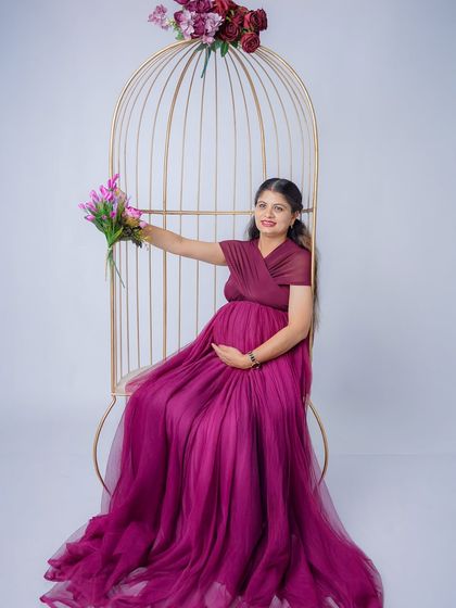A joyful solo portrait with the mom-to-be holding a bouquet of flowers. Her bright smile and the beautiful purple gown radiate happiness.