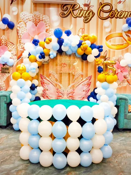 A close-up of the ring ceremony table, which is creatively constructed from white and blue balloons. The butterfly wings add a touch of whimsy.