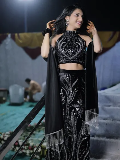 A client looking radiant in a custom black fish-cut lehenga set. The entire outfit is covered in shimmering sequin work, making it a showstopper for any evening celebration like a sangeet or reception.
