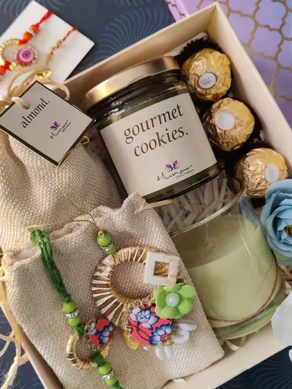 We design hampers that celebrate every bond, like this special Rakhi gift box. It combines a beautiful lumba rakhi set with gourmet cookies, a scented candle, and other treats to make the occasion memorable.