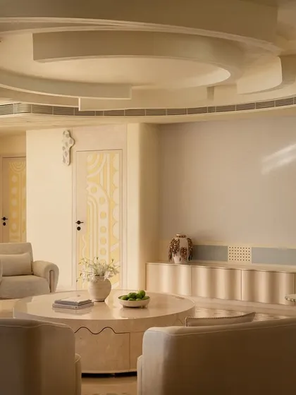 The living space in our 'Soft Serve' project is imagined as a series of intersecting circles. Curvilinear sofas and a sculptural ceiling design create a hypnotic visual of ripples and waves, all in a calming, ecru-toned palette.