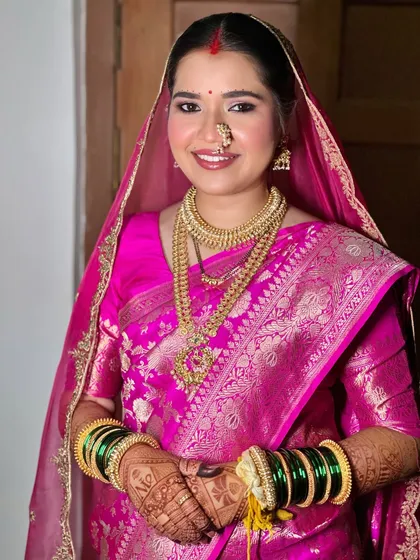 A classic portrait of the happy bride. The combination of the pink saree, green bangles, and gold jewelry is iconic, and the makeup ties it all together perfectly.