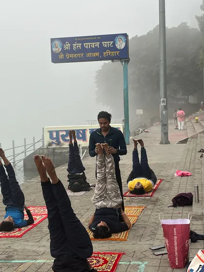 Guiding students in Sarvangasana (shoulder stand), an inversion that calms the nervous system, made even more special by the riverside setting.