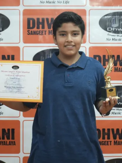 A young artist proudly holds his certificate and trophy.