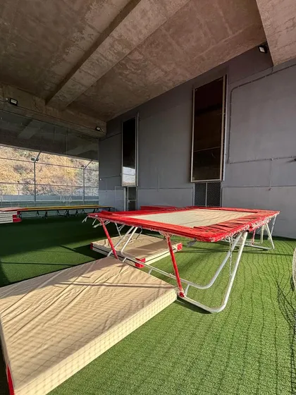 My gymnastics area basking in the golden hour light. The trampolines and safety mats are all set up, ready for athletes to come and practice their skills in a serene and inspiring setting.