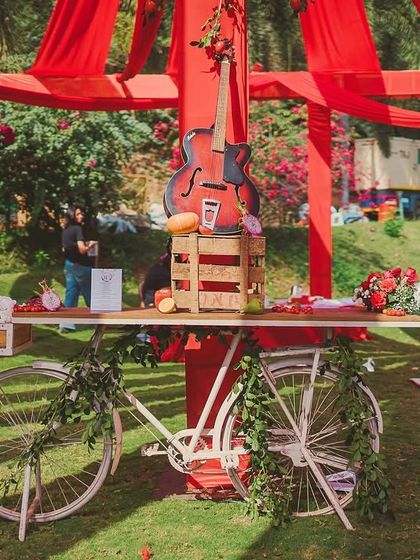 A vintage bicycle repurposed as a decorative table, adorned with greenery and a cello. This quirky element adds to the artistic and bohemian street-fair vibe of the event.