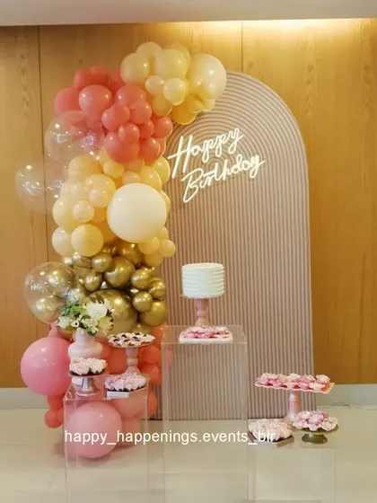 This setup shows how minimalist decor can be incredibly elegant. I used a textured arch backdrop with a simple neon sign and a cascading balloon garland in soft pastel and gold tones. The clear acrylic plinths for the cake and desserts add a modern, clean touch.