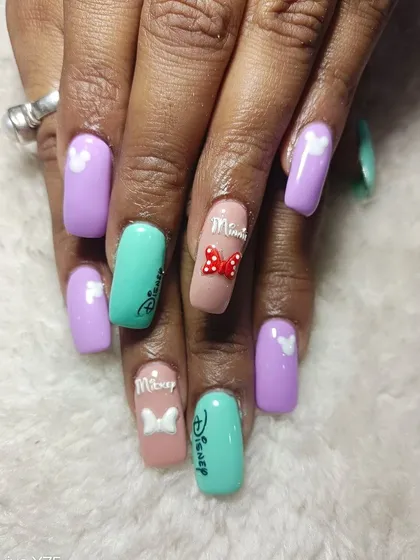 A close-up of these adorable Disney themed nails. The details include a 3D Minnie Mouse bow and the classic Disney logo.