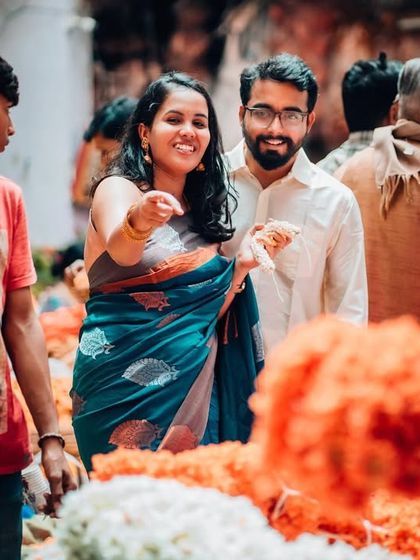 A couple enjoys shopping for flowers together in a busy market, a perfect example of a candid and interactive pre-wedding shoot theme.