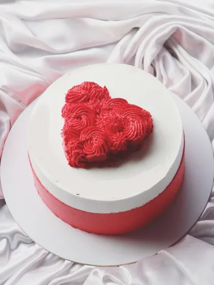 A classic red and white bento cake with a piped frosting heart in the center. It's a perfect little cake for two.