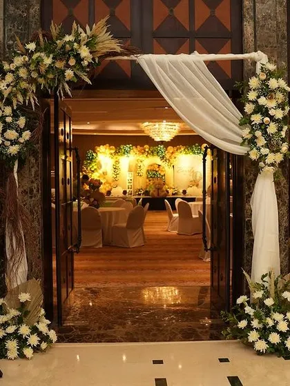 An elegant floral and drapery archway welcomes guests to this green and gold teddy bear baby shower. The entrance provides a beautiful glimpse into the main event space, setting a sophisticated tone.