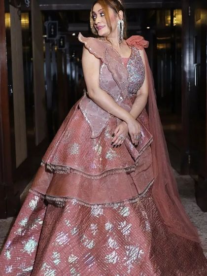 A full shot of the tiered rose-colored gown, showcasing its structured layers and one-shoulder floral detail.