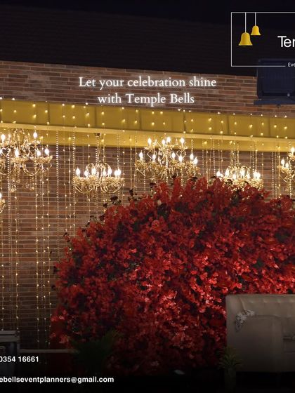 We transform venues into masterpieces. This decor features a white facade adorned with cascading pink florals and ornate golden chandeliers for a luxurious feel.