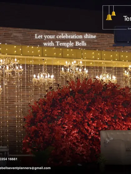 We transform venues into masterpieces. This decor features a white facade adorned with cascading pink florals and ornate golden chandeliers for a luxurious feel.