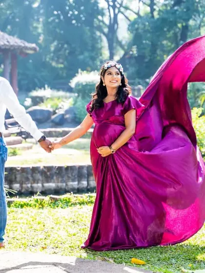 A dynamic shot of a couple walking in the park, the wind catching the train of the mom-to-be's beautiful magenta gown.