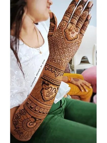A candid shot of a bride showing her beautiful back-hand mehndi, filled with traditional patterns and a peacock motif.