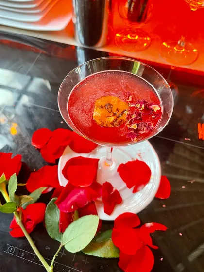 A romantic cocktail garnished with fresh rose petals and a single dried rosebud. Using edible flowers adds a touch of elegance and a subtle floral aroma to the drink.