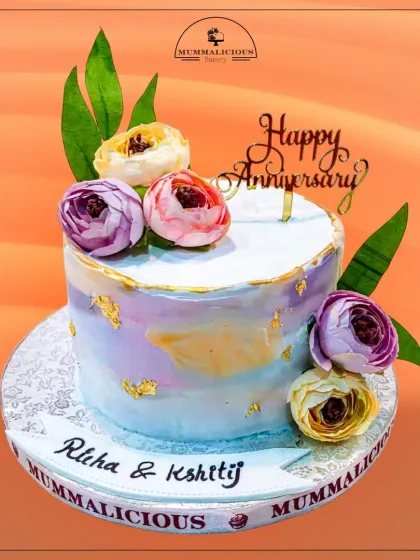 A beautiful watercolour-effect anniversary cake. The soft pastel hues, gold leaf, and delicate sugar flowers create an artistic and elegant design, personalized for Richa and Kshitij's celebration.