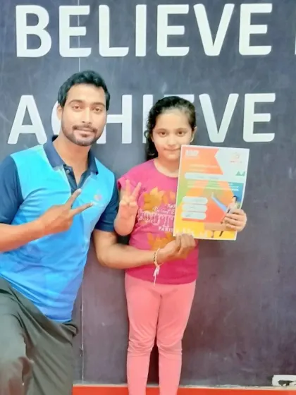 A proud coach celebrates with his student after she earned her latest gymnastics certificate. These moments build a strong and positive student-coach relationship.