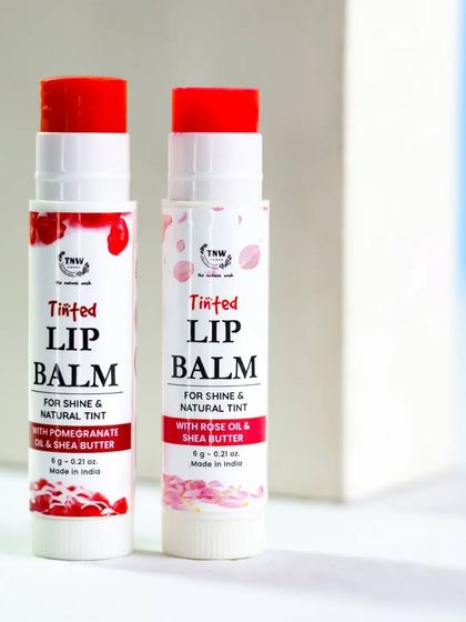 Two tinted lip balms stand against a clean, geometric background. This simple, graphic composition puts the focus on the products' vibrant colors and sleek packaging.