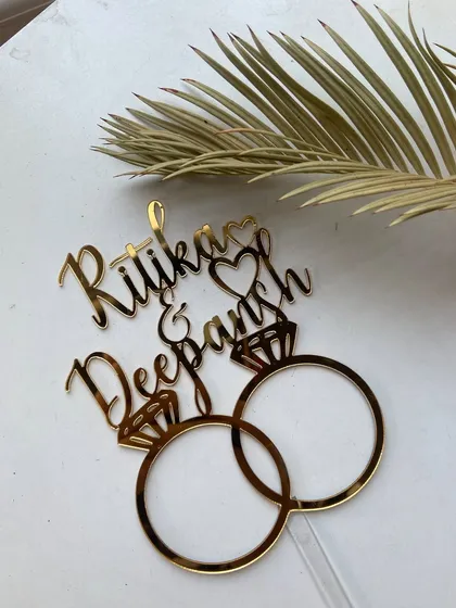 A top-down view of the "Ritika & Deepansh" topper, highlighting the clean, precise cuts of the design.