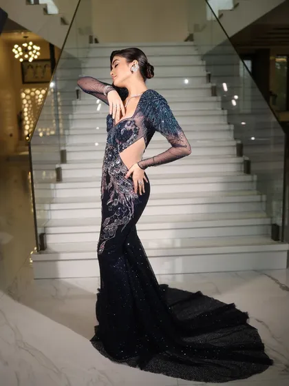 A full-length pose of the model in a stunning, form-fitting blue gown, exuding confidence and glamour.