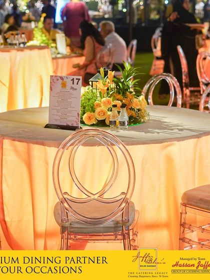 We act as your premium dining partner for all occasions. This image captures an elegant table setting with modern transparent chairs and a warm, inviting color palette, ready for guests to enjoy an evening of fine food and celebration.