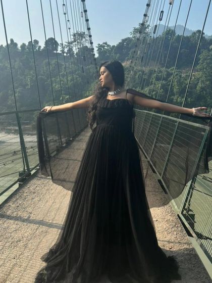 A happy customer in a beautiful black pre-wedding gown, posing on a bridge. This shows how my gowns are perfect for creating dramatic photoshoot moments.