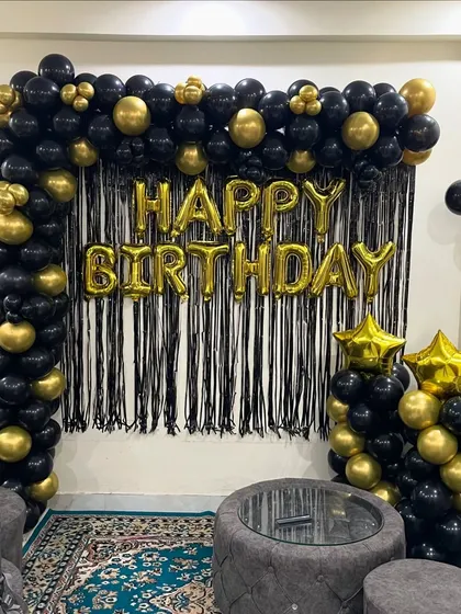 A closer view of the black and gold balloon arch and "Happy Birthday" foil letters, perfect for a home party.