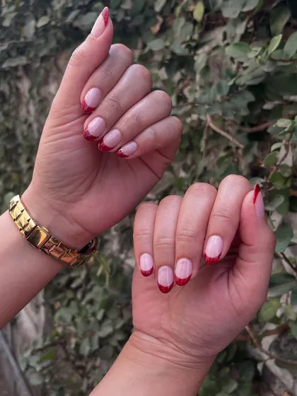French nails with a subtle twist. This design features classic French tips, but with a sparkling red glitter polish for a pop of color and fun.