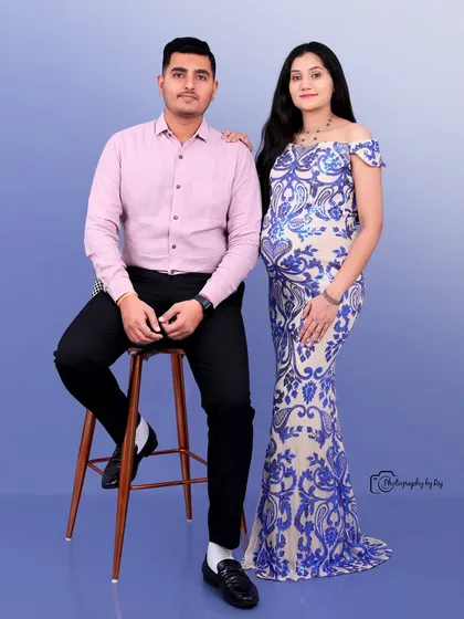 A classic studio portrait of a couple, with the mother-to-be in a blue and white sequined gown.