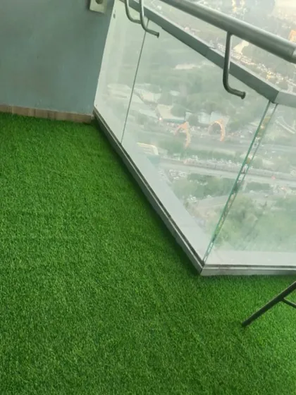 The glass railing on this high-rise balcony reflects the green of the new artificial grass floor.