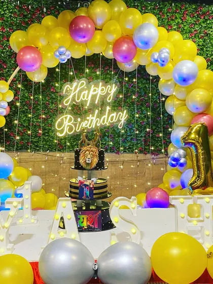 The main cake table setup for Yash's party, featuring a lion-themed cake, marquee letters, and the balloon ring backdrop.