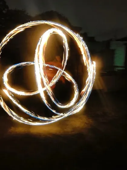 This is a long exposure shot of me spinning fire poi. It captures the light trails and creates a beautiful, static image of the patterns I weave in the air, in this case, a triquetra.