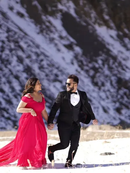 A candid, happy moment of the couple walking through a snowy field. The bright gown adds a wonderful pop of color against the white and brown landscape.