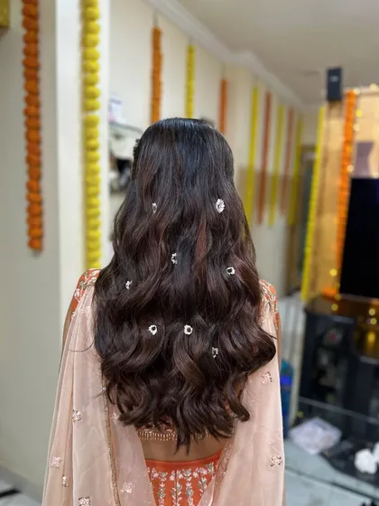 The back view of the daisy-adorned hairstyle. The small flowers add a delicate and unique detail to the soft waves.