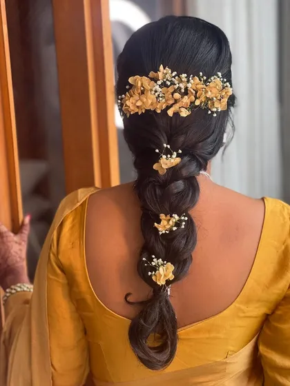 A simple and elegant bubble braid adorned with delicate yellow flowers. This is a beautiful and fuss-free hairstyle for a Haldi or Mehendi ceremony.