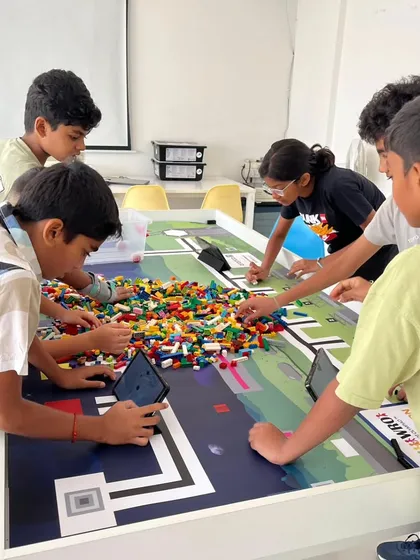 The fun begins with a single brick. Here, a group of our students dives into a pile of LEGOs, working together to build the game elements for the World Robot Olympiad, turning a complex challenge into an exciting, hands-on construction project.