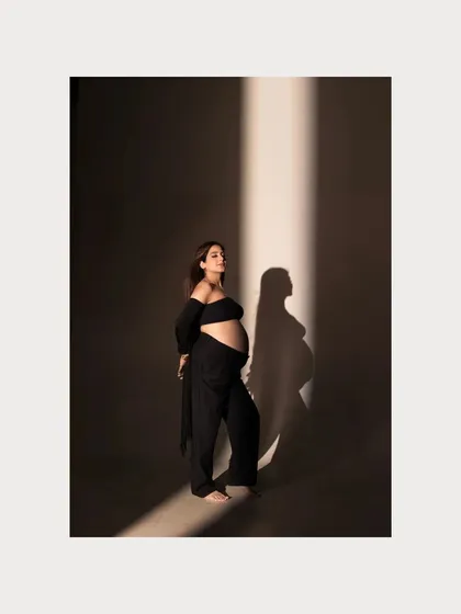 A modern, artistic portrait using a single beam of light to create a dramatic and powerful silhouette. This studio shot highlights the beauty of the baby bump with a high-fashion feel, showing that maternity photography can be both emotional and strikingly artistic.