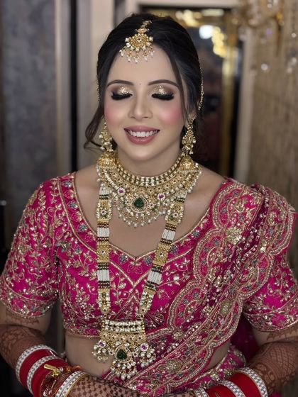 A close-up of this bride's regal wedding look. The gold glitter eyeshadow and soft pink lips are a classic combination that works beautifully with her pink lehenga.