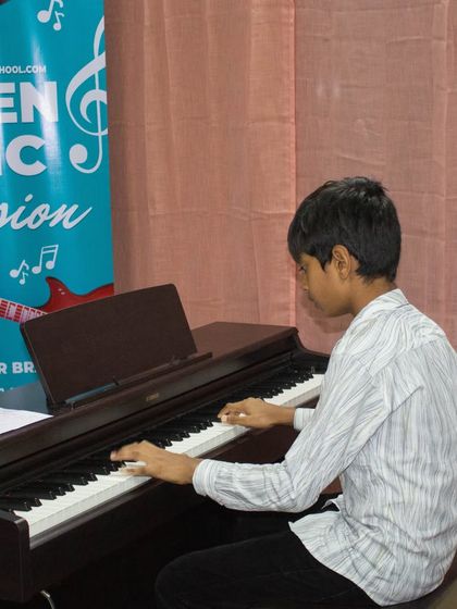 A student performs on an upright piano at the Sarjapur open mic.